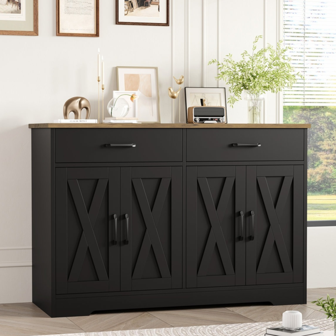 A black sideboard with two drawers and four cabinet doors featuring an X design, topped with decorative items like vases, candles, and artwork.