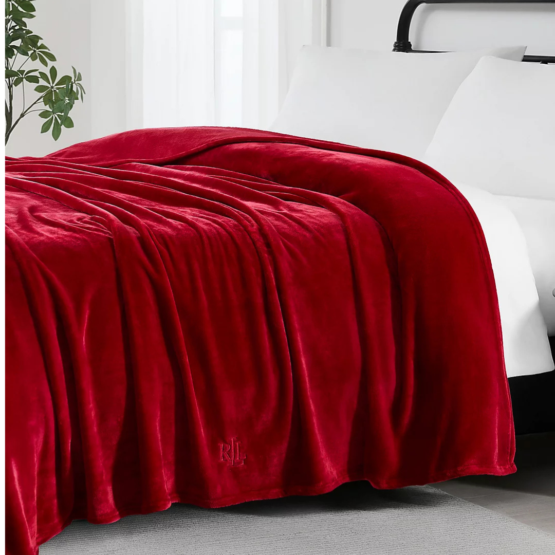 Ralph Lauren King Micromink Blanket in a deep red color, featuring a soft, plush texture with an embossed \“RL\“ logo, draped over a bed.