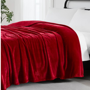 Ralph Lauren King Micromink Blanket in a deep red color, featuring a soft, plush texture with an embossed \“RL\“ logo, draped over a bed.