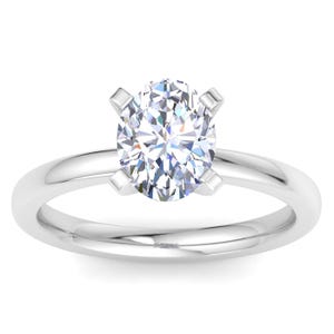 A sleek ring with a central oval-cut diamond, held by four prongs, set on a polished metal band.