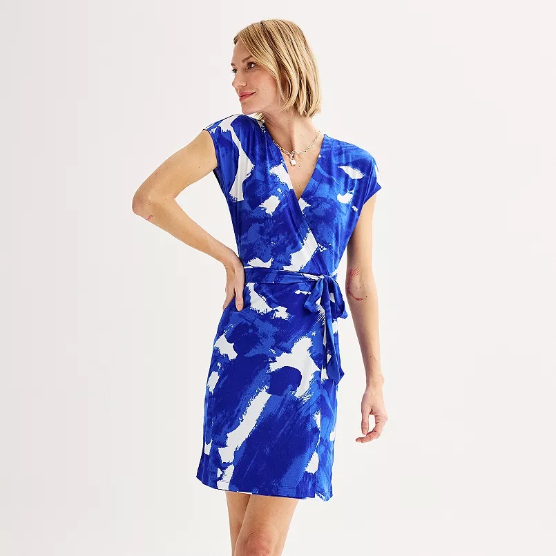 A woman models a blue and white patterned wrap dress with a V-neckline and a side tie.