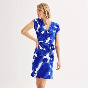 A woman models a blue and white patterned wrap dress with a V-neckline and a side tie.