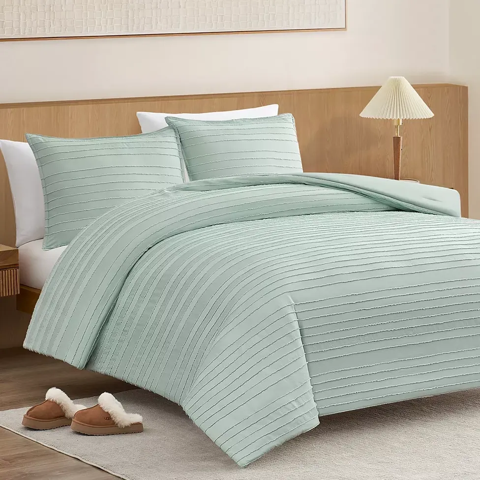 A bedroom setting featuring a light green textured duvet cover with matching pillow shams on a wooden bed frame, accompanied by a pair of plush slippers on a light rug.