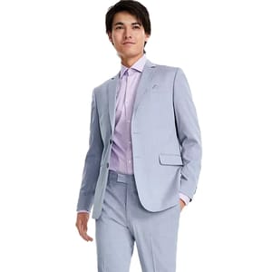 A man wearing a light blue suit with a lavender checkered shirt and a matching tie.