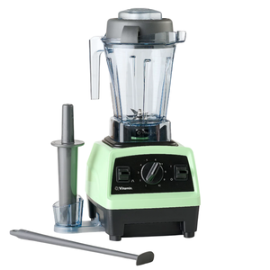 A Vitamix blender with a mint green base and a clear blending container is shown alongside a tamper tool.