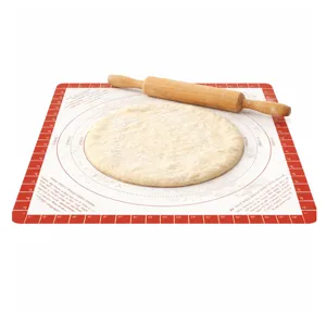 A silicone baking mat with measurement guides features a round, flattened dough and a wooden rolling pin.