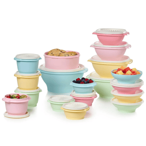 A collection of pastel-colored plastic storage bowls with lids, varying in size, filled with cookies, fruits, and vegetables.