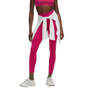 A person is wearing a pink athletic outfit, consisting of a sports bra and leggings, with a white shirt tied around the waist and white sneakers.