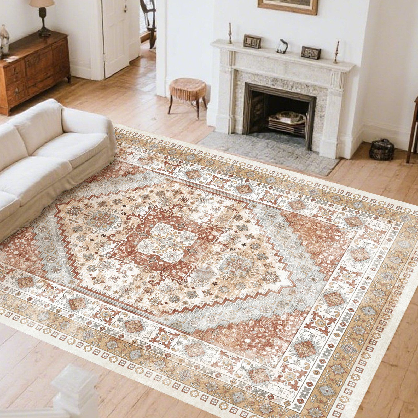 A living room with a large, intricately patterned area rug featuring earthy tones. The room includes a white couch, a marble fireplace, a small round stool, and a wooden dresser, creating a cozy and elegant atmosphere.