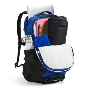 A blue and black North Face Borealis Backpack is shown packed with items including a laptop, a water bottle, a notebook, a rolled-up jacket, and a blue garment.