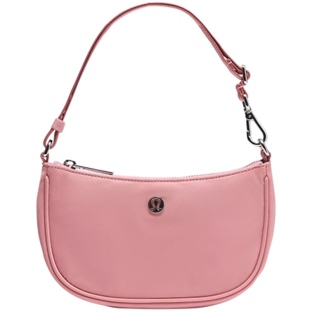 A small pink shoulder bag with a detachable strap featuring metal clips. It has a zipper closure and displays a circular logo emblem on the front.