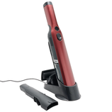 A red handheld vacuum cleaner with a charging base and a detachable nozzle accessory.
