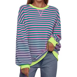 The oversized striped sweatshirt features green and pink horizontal stripes, with neon green cuffs and collar. It's styled with loose, long sleeves and is paired with blue jeans.