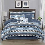 Bedding set featuring a rustic theme with patterns of bears and trees on a blue and white background, including a comforter, pillows, and shams, complemented by a plaid design.