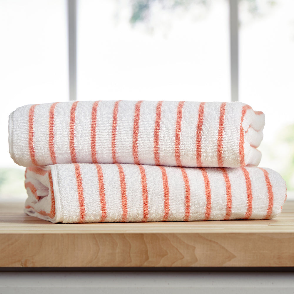 Two white cotton cabana towels with orange stripes, stacked neatly.