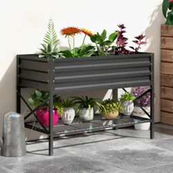 Metal raised garden bed with colorful plants above; lower shelf holds small potted plants and a watering can sits beside it on a patio.