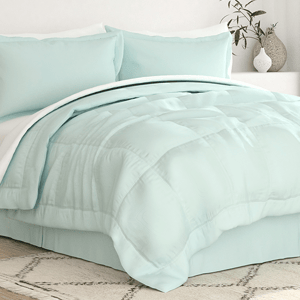 A light blue 8-piece queen comforter and sheet set featuring a quilted comforter, two pillow shams, a fitted sheet, a flat sheet, and pillowcases, styled simply with a plant vase in the background on a light-colored rug.