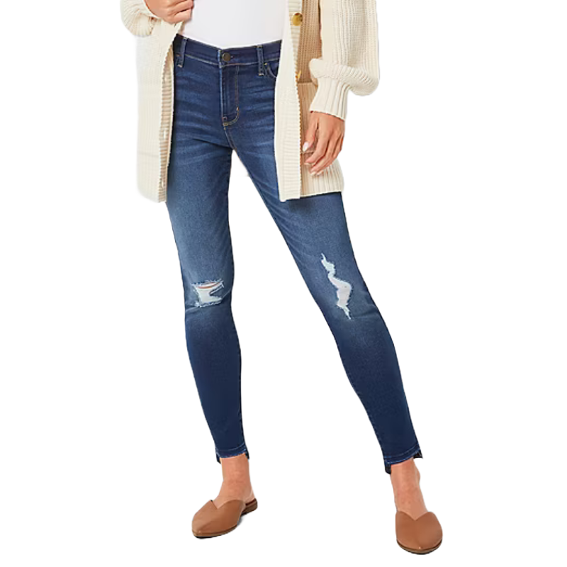 A person is wearing ripped blue skinny jeans paired with a cream cardigan and brown loafers.