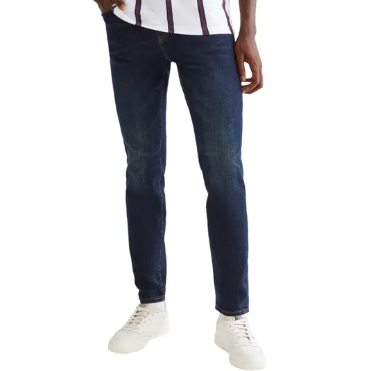 Dark blue slim-fit jeans paired with white sneakers and a striped shirt.