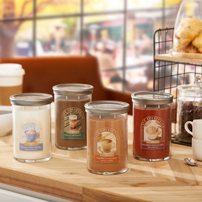 Four scented candles with labels indicating different coffee-flavored aromas: Peppermint Mocha, Nitro Cold Brew, Vanilla Chai Latte, and Pumpkin Spice Latte.