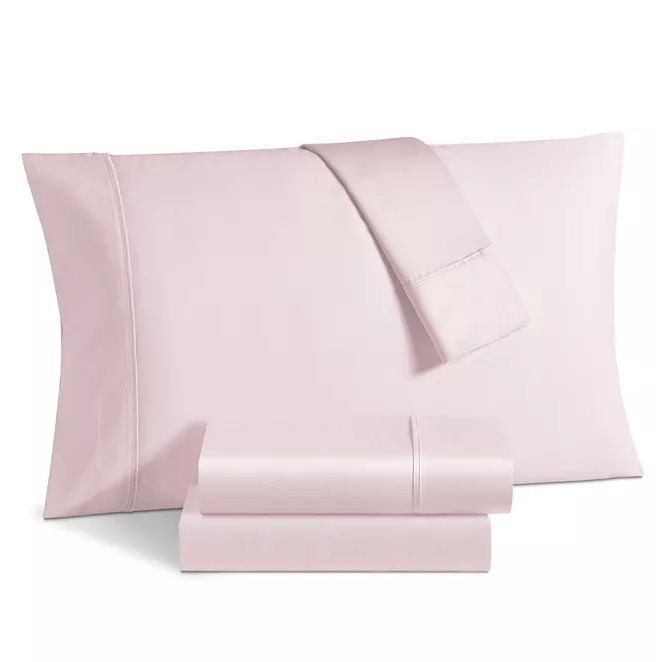 A set of light pink bed sheets includes a pillowcase, a flat sheet, and a fitted sheet with a smooth, satin-like finish.