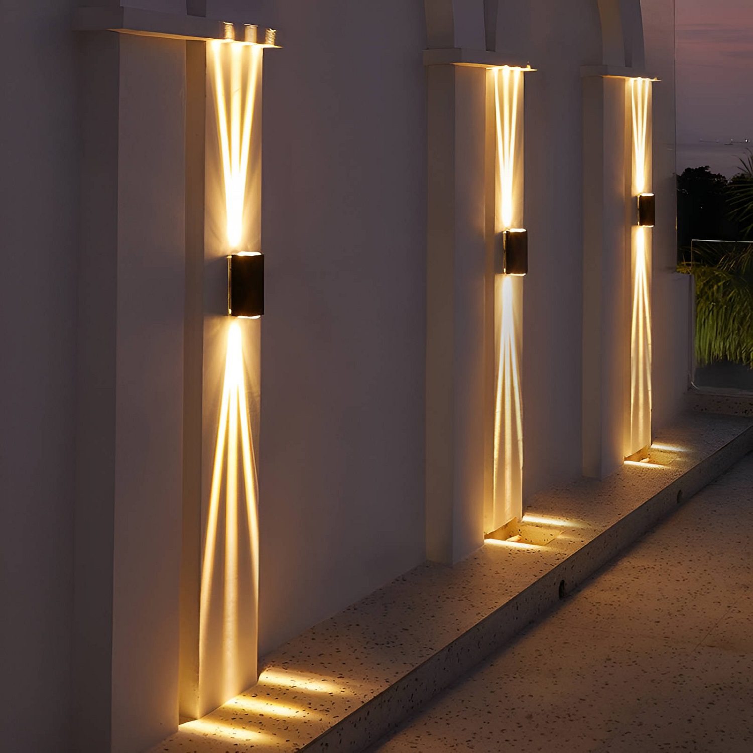 Wall-mounted exterior lights with a vertical beam effect on a twilight background.