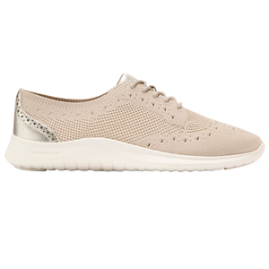 A beige knit sneaker with decorative perforations, a white sole, and metallic heel accents.