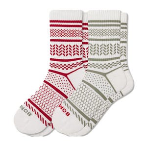 A pair of crew socks with geometric patterns, one in red and white and the other in olive and white. Each sock features brand lettering near the toe.