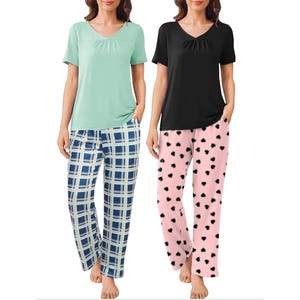Two women wearing pajama sets: one with a mint green top and blue plaid pants, the other in a black top with pink pants featuring black heart patterns.