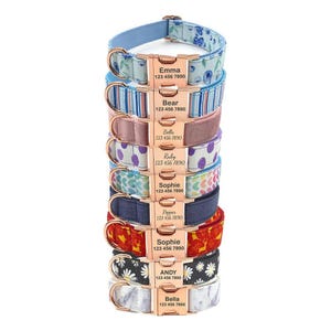 A stack of personalized pet collars with various patterns and colors, each with a name and phone number on a metal tag.