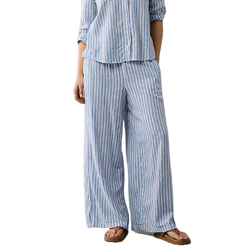 Women's blue and white striped linen pants with a relaxed fit and elastic waistband, paired with a matching button-down shirt and brown sandals.