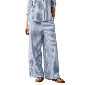 Women's blue and white striped linen pants with a relaxed fit and elastic waistband, paired with a matching button-down shirt and brown sandals.