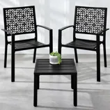 Two black patio chairs with intricate lattice back designs are paired with a matching square side table. A small potted plant is placed on the table.