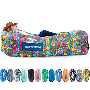 The Chillbo Swaggins Inflatable Couch displays a vibrant, psychedelic paisley design and includes an individual reclining on it with a hat, showcasing various color options below.