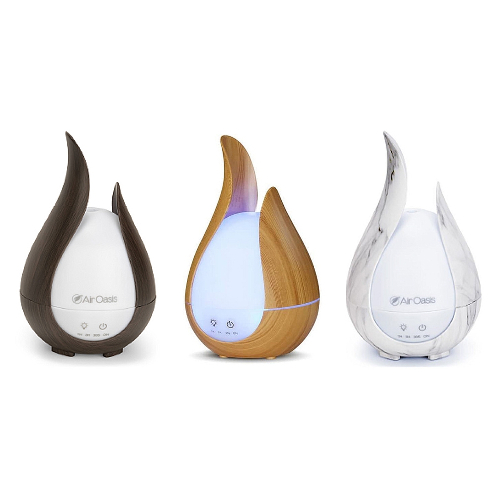 Three teardrop-shaped essential oil diffusers with a flame design: one in dark wood, one in light wood with a blue light, and one in marble finish.