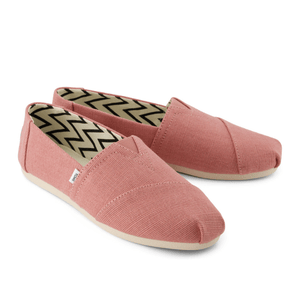 Pair of pink slip-on canvas shoes with a zigzag pattern inside, featuring beige soles and a small brand tag on the side.