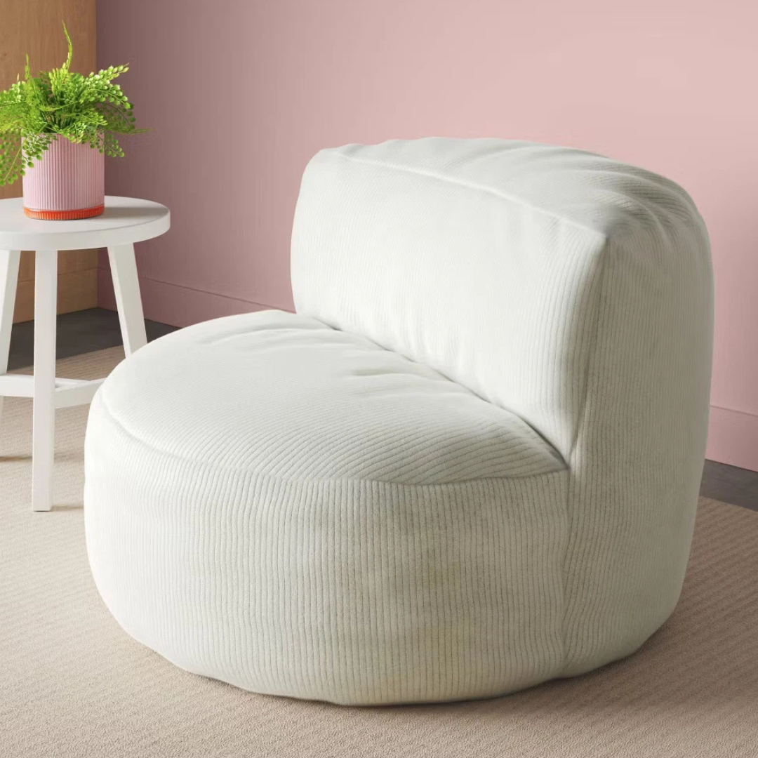 A white, cushioned lounge chair with ribbed texture is placed next to a small round table holding a pink potted plant against a pink wall.