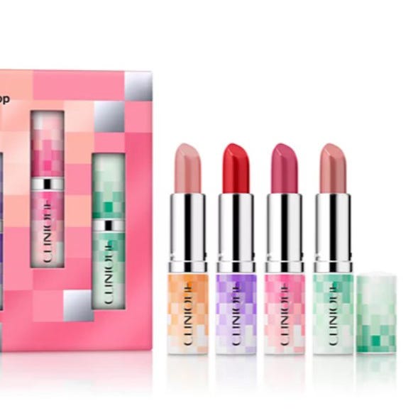 A set of five Clinique lipsticks in varying shades from nude to deep red, housed in metallic cases with multicolored bases, accompanied by a pink and multicolor box.