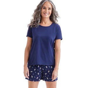 A woman is wearing a navy blue short-sleeve shirt and navy floral shorts.
