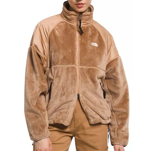 The North Face Velour Jacket is a tan, plush zip-up with a high collar and contrasting smooth fabric on the upper shoulders and arms. It features side pockets and an embroidered logo on the chest.