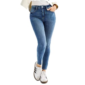 Blue high-waisted skinny jeans paired with white sneakers featuring black stripes, worn with a black belt and a white top partially covered by a beige jacket.