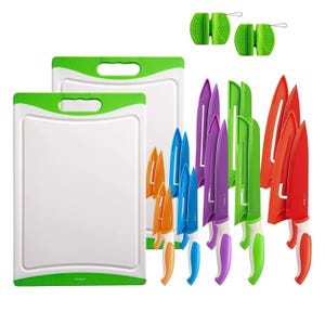 A set of colorful kitchen knives with matching sheaths and two white cutting boards with green handles.
