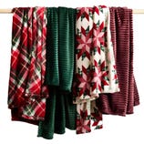 Four hanging blankets with various patterns and textures, featuring plaid, green ribbed, and red star designs.