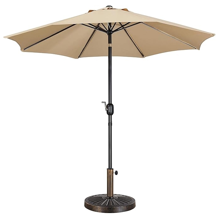 A 9-foot beige patio umbrella with a crank handle for easy opening and closing, supported by a sturdy black pole and a circular, weighted base.
