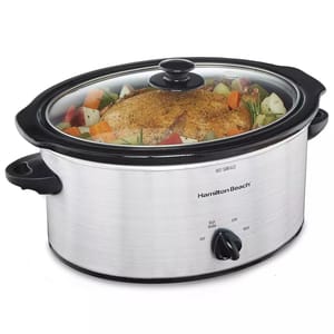 Hamilton Beach brand slow cooker with a clear lid, containing a seasoned roast and vegetables. Features include a dial with \“Keep Warm\“, \“Low\“, and \“High\“ settings.