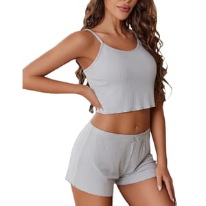 A woman is wearing a light gray, ribbed loungewear set consisting of a sleeveless crop top and matching shorts.