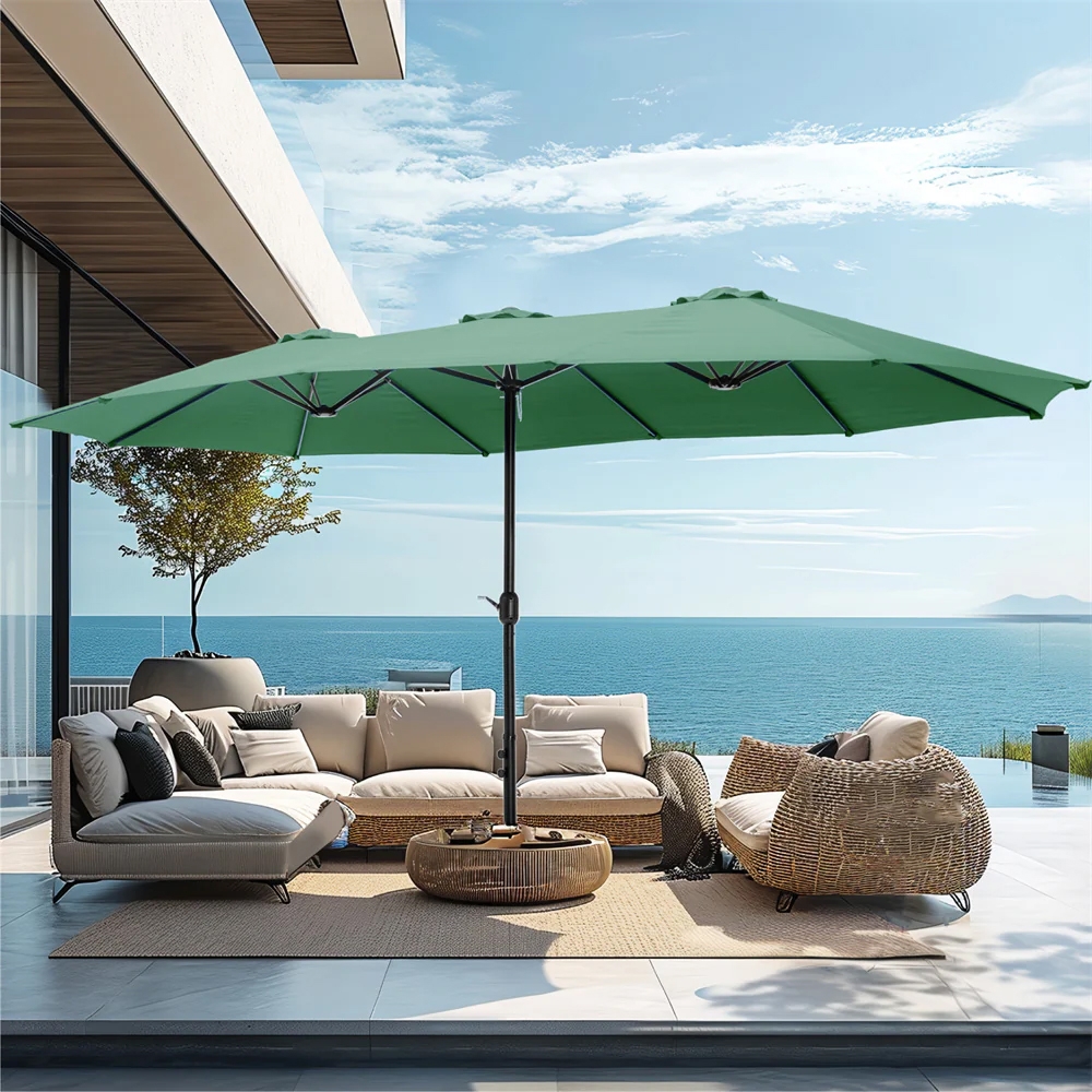 Outdoor seating area featuring a beige sectional sofa, wicker armchair, center table, and a large green patio umbrella, with an ocean view backdrop.