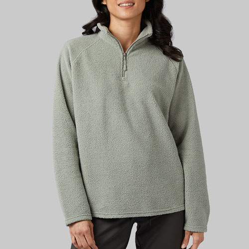 A person is wearing a light green sherpa fleece pullover with a quarter-zip neckline and long sleeves. The fleece has a raised, textured surface and a casual fit.