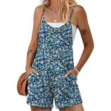 A woman is wearing a blue floral romper with spaghetti straps over a white tank top. She accessorizes with layered necklaces, bracelets, a tattoo of a rose on her arm, and holds a brown woven bag.