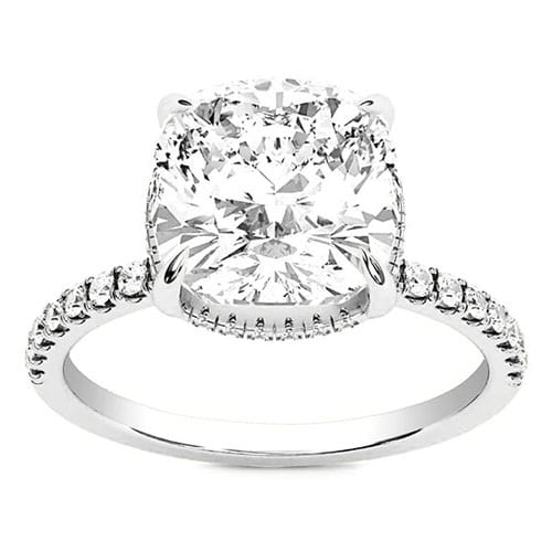 A silver-toned ring featuring a large cushion-cut diamond set in a four-prong setting, with a band adorned with smaller round diamonds.